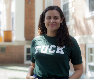 Tuck student standing in front of Tuck Hall wearing a tshirt that says Tuck