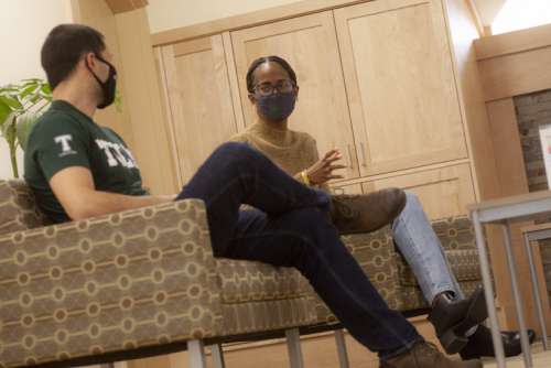Two students speaking with one another; masked