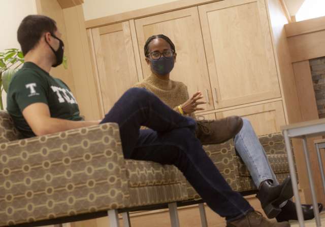 Two students speaking with one another; masked
